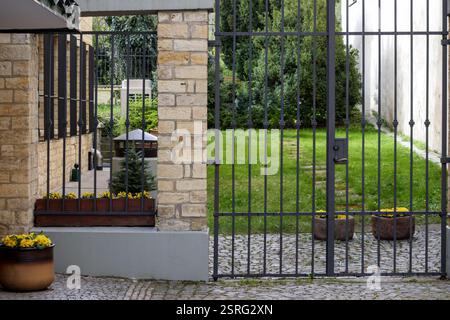 Eisenzaun mit Blumentöpfen auf dem Bürgersteig. Stockfoto