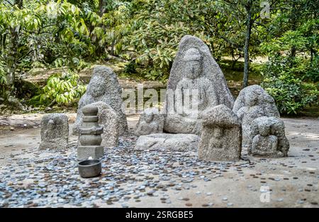 Japanische kleine Jizo-Statuen und viele Münzen auf dem Boden für Glück und Glück im buddhistischen Kinkakuji-Zen-Tempel in Kyoto. Stockfoto