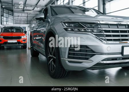Vorderansicht des modernen neuen silberfarbenen Autos und eines roten hinter dem Auto. Stockfoto