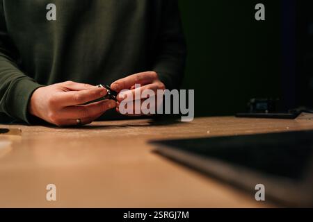 Nahaufnahme eines Technikers, der die Batterie der Smartwatch mit speziellen Werkzeugen ersetzt, um den komplizierten Prozess moderner Gerätereparaturen zu verdeutlichen. Stockfoto