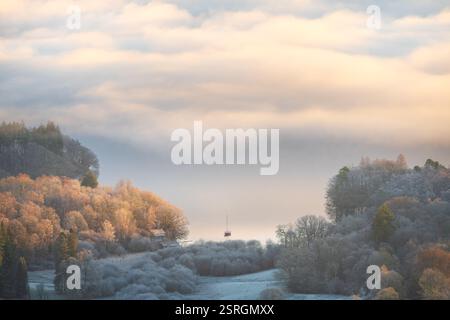Ein einsames Segelboot auf einem ruhigen nebeligen See von Windermere mit wunderschönem Winterlicht. Lake District, Großbritannien. Stockfoto