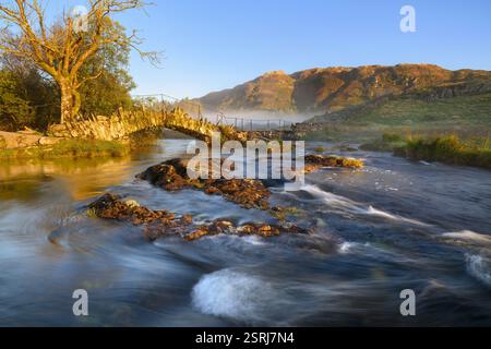 Die Slaters Bridge überquert den Fluss in Little Langdale, Lake District, Großbritannien. Stockfoto