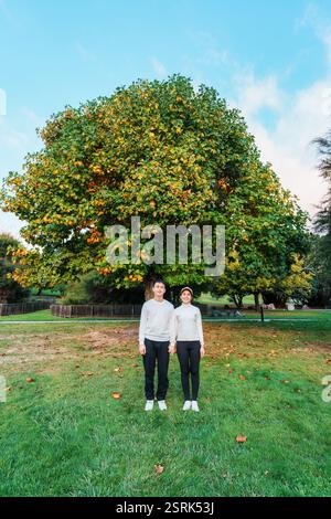 Glückliches asiatisches Paar genießt zusammen mit Ahornbaum im Park an sonnigen Tagen Stockfoto
