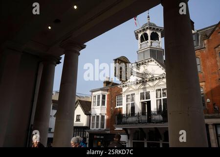 Fußgänger passieren den verzierten Uhrenturm und das Rathaus auf dem historischen Marktplatz von Guildford, Großbritannien. Stockfoto