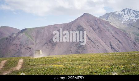 Der alte Armeewagen fährt auf einer staubigen Straße in Richtung Berge, Pamir Berge, Kirgisistan Stockfoto