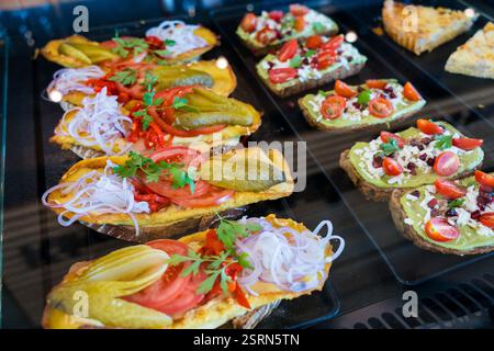 Verschiedene offene Sandwiches mit frischen Belägen in einer Vitrine. Stockfoto