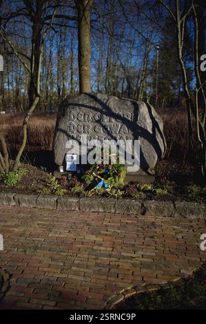 Flensburg, Schleswig-Holstein das Bild zeigt einen Gedenkstein im Carlisle-Park in Flensburg mit der Inschrift den Opfern der Gewaltherrschaft. Vor dem Stein liegen eine Kranzniederlegung mit Tannenzweigen und Zapfen sowie eine blau-gelbe Schleife, die auf die Ukraine hindeuten könnte. Daneben stehen mehrere Grablichter und ein gerahmtes Foto mit einer Gedenkinschrift zu Alexej Nawalny. Die Szenerie ist von Sonnenlicht durchziehen, wobei Baumäste Schatten auf den Stein werfen. Änd. 16. Februar jährt sich der Todestag des russischen Oppositionsführers Alexej Nawalny. Er starb am 16. Februar 2024 i Stockfoto