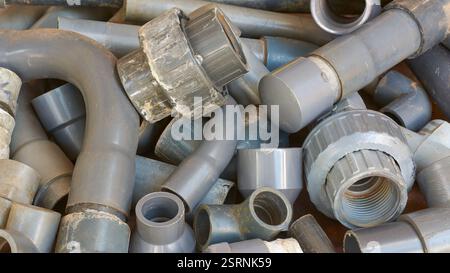 Stapel gebrauchter, entsorgter pvc-Rohre und -Fittings im Vollrahmen, Winkelkupplungen und Rohrabschnitte, Industrie- oder Baustoffrecycling und Abfall Stockfoto