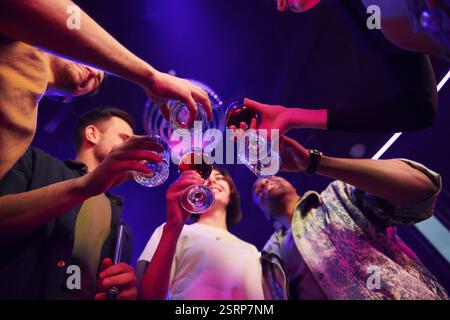 Die Brille in den Händen halten. Gruppe von Freunden, die gemeinsam Spaß im Nachtclub haben. Stockfoto