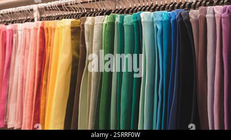 Eine bunte Hose mit einem Regenbogen aus Farben. Die Hosen hängen an einem Gestell und sind in verschiedenen Farben Stockfoto