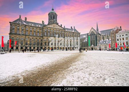 Verschneite Dam in Amsterdam Niederlande im Winter bei Sonnenuntergang Stockfoto
