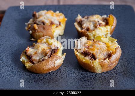 Köstliche gefüllte Kartoffeln nach Taco-Art, gefüllt mit gewürztem Fleisch, geschmolzenem Käse und aromatischen Gewürzen. Serviert auf einem eleganten Teller, bieten sie eine Perfec Stockfoto