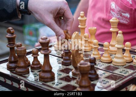 Zwei Männer, die draußen Schach spielen, von Angesicht zu Angesicht mit einem hölzernen Schachbrett und Schachfiguren, UK. Konzept: Strategie, Hobby für Erwachsene, Hobbys für Erwachsene, Brettspiel Stockfoto