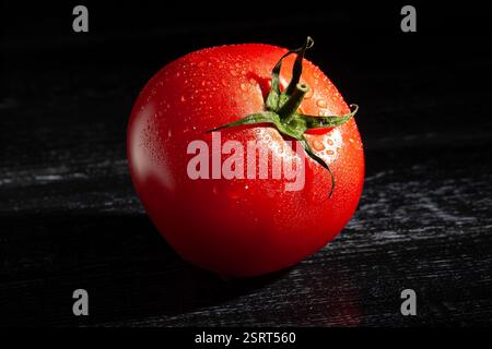 Tomate auf schwarzem Holz Hintergrund nass Stockfoto