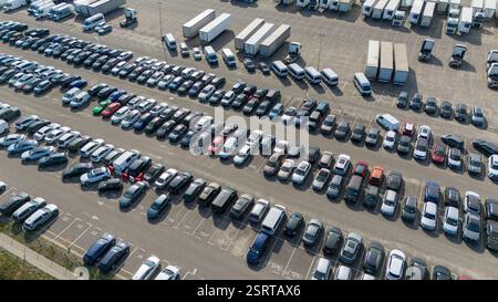 Blick aus der Vogelperspektive auf einen großen Parkplatz mit Reihen geparkter Autos und LKWs. Stockfoto