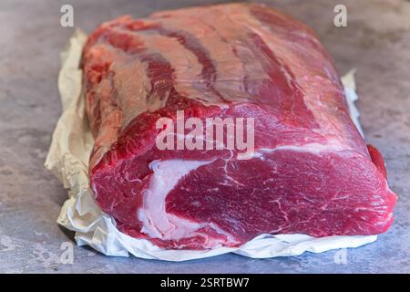 Ein ganzer, frischer, roher Rinderribeye-Joint sitzt, mit Details, die einen fetten Marmor auf dem saftigen Gesicht des Steaks zeigen. Stockfoto