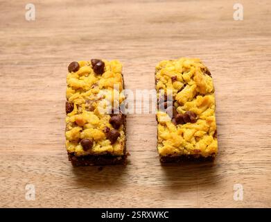 Schokoladen-Chip-Keksriegel sitzen auf einer hölzernen Arbeitsplatte mit goldener gelber Kruste und Schokoladen-Häppchen. Perfekt zum Teilen während gath Stockfoto