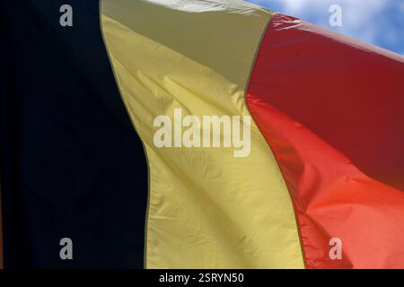 belgien Flagge , weht im Wind mit blauem Himmel auf dem Hintergrund Stockfoto