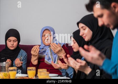 Die muslimische Familie macht iftar dua zusammen, um das Fasten während des Ramadan Esstisch zu Hause zu brechen. Stockfoto