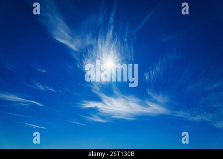 Helle Sonne, die durch wackelige Wolken im blauen Himmel scheint Stockfoto