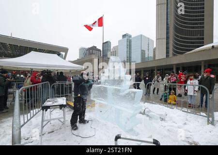 Toronto, Kanada, 15. Februar 2025. Ein Eisbildhauer schuf am 15. Februar 2025 eine Ahornblatt-Eisskulptur unter einer riesigen kanadischen Flagge auf dem Platz der Toronto City Hall in Toronto, Kanada. Am 15. Februar wurde vor dem Rathaus eine riesige kanadische Flagge mit einer Länge von 30 Metern und einer Breite von 15 Metern gehisst, um den 60. Jahrestag der Einweihung der kanadischen Flagge zu feiern. Quelle: Yu Ruidong/China News Service/Alamy Live News Stockfoto