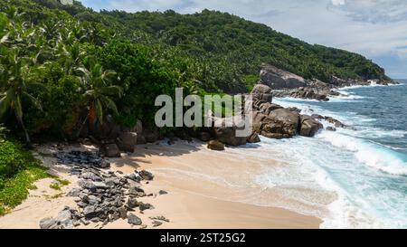 Tropischer Strand mit klarem türkisfarbenem Wasser und felsigen Ausläufern. Seychellen, Mahe. Anse Boileau. Stockfoto