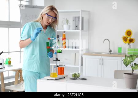 Wissenschaftlerin mit Probenkolben, Sonnenblumensamen und Sprossen im Labor Stockfoto