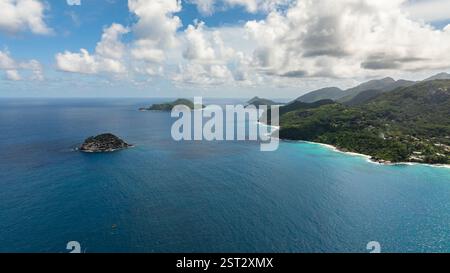 Türkisfarbenes Wasser trifft auf den Felsvorsprung entlang einer üppig grünen Küste, die sich zum Horizont hin erstreckt. Seychellen, Mahe. Stockfoto
