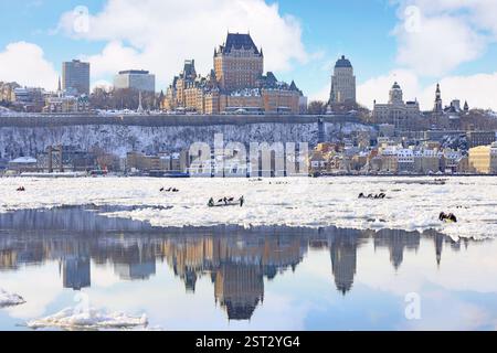 Traditionelles Eiskanu-Rennen von Quebec nach Levis während des Winterkarnevals mit der Skyline der Stadt auf dem gefrorenen Saint Lawrence River Stockfoto