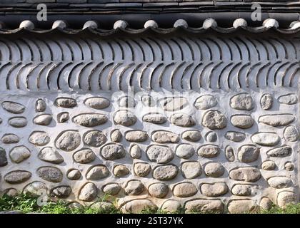 Orientalische dekorative Wand eines traditionellen koreanischen Hauses mit Dachziegel. Orientalischer horizontaler Hintergrund mit altem Steinzaun, Südkorea Stockfoto