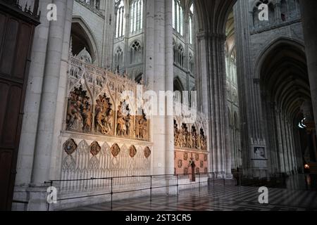 Ein detaillierter Blick auf komplizierte mittelalterliche Schnitzereien an einer Kathedralmauer mit biblischen Szenen, umgeben von großer gotischer Architektur. Stockfoto