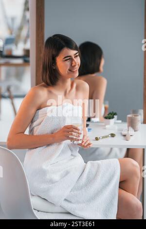 Lächelnd und mit einem Glas zu trinken. Die junge Frau ist zu Hause. Vorstellung von Schönheit. Stockfoto
