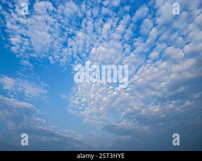 Eine faszinierende Drohnenansicht mit flauschigen weißen Wolken, die sich über einen leuchtend blauen Himmel verstreut haben, schafft eine friedliche und ruhige Wolkenlandschaft. Stockfoto
