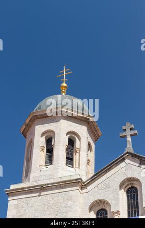Eine traditionelle Kirche mit Mauerwerk und Glockentürmen vor einem leuchtend klaren blauen Himmel. Die architektonischen Details und das harmonische Design spiegeln seine wider Stockfoto