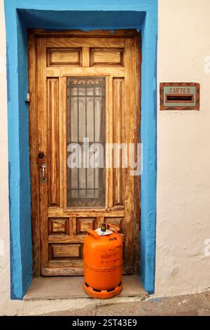 Madrid, Spanien - 13. Februar 2025: Hauseingang mit Holztür und traditioneller Metall-Butangasflasche am Eingang Stockfoto