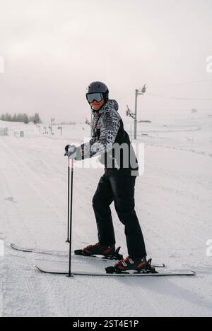 Lächelnder Skifahrer, der auf der Piste steht und in die Kamera blickt Stockfoto