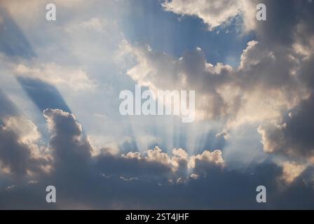 Sonnenstrahlen brechen tagsüber durch dramatische Wolken am Himmel Stockfoto