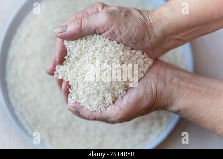 Zwei Frauenhände mit Jasminreis, Reis fällt aus den Händen, gesundes und biologisches Konzept. Draufsicht Stockfoto