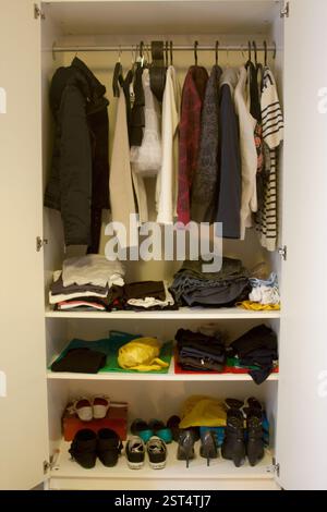 Im offenen Kleiderschrank finden Sie organisierte Kleidung und Schuhe. Aufbewahrungslösungen, die Organisation von Wandschränken und ein Blick in den persönlichen Stil. Stockfoto