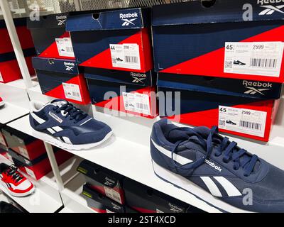 Lemberg, Ukraine - 16. Februar 2025: Marineblaue sportliche Reebok-Sneakers mit Markenkartons auf Regalen im Einzelhandel Stockfoto