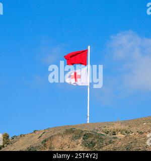 Rote Warnflagge und cruz roja Flagge an der Rettungswache, Piedra Playa, Fuerteventura, Kanarische Inseln, Spanien, EU. Aufgenommen Im Winter 2024 Stockfoto