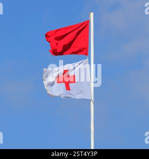 Rote Warnflagge und cruz roja Flagge an der Rettungswache, Piedra Playa, Fuerteventura, Kanarische Inseln, Spanien, EU. Aufgenommen Im Winter 2024 Stockfoto