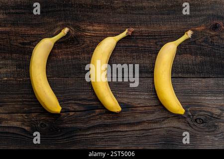 Bananen auf einem Holztisch. Ein reifer, gelber Bananenstrauch auf dem Küchentisch. Stockfoto
