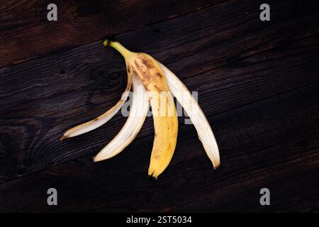 Bananenschale auf einer Nahaufnahme im dunklen Hintergrund. Bananenschale auf braunem Holzboden Stockfoto