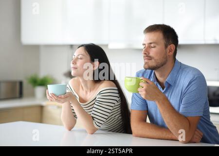Interrassisches Paar, das zu Hause in der Küche trinkt und atmet Stockfoto