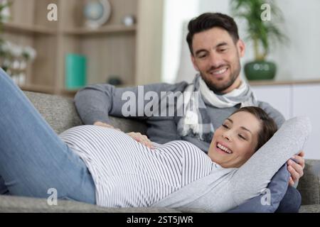 Schwangere Frau und gutaussehender Mann, der zu Hause auf dem Sofa liegt Stockfoto
