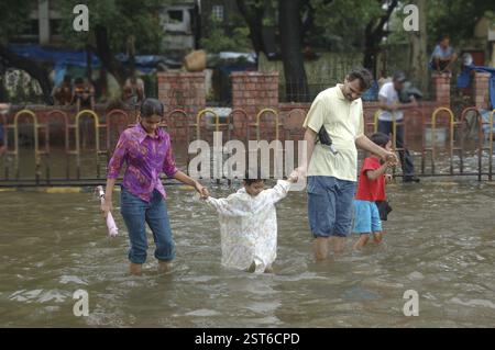 Überschwemmung aufgrund von starkem Regen, zeigt Erziehungsberechtigten, die Kinder in angesammeltem Regenwasser, Monsoon, Weltrekordregen auf der Straße von Jambhali aka nach Thane Sta Stockfoto