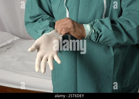 Junger indischer Arzt mit Operationshandschuhen Stockfoto