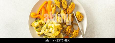 Diese geschmackvolle Mahlzeit umfasst gebratene Zucchini-Blüten in goldenem Teig, ein zartes Blumenkohlomelett mit gedünsteten Paprika, ideal für eine gesunde Ernährung, Banner Stockfoto