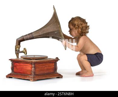 Baby wird neugierig durch ein altes Gramophon Stockfoto